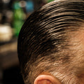 Close-up overhead view of dark hair combed back with a slick, low-shine finish after applying Imperial Blacktop Pomade.